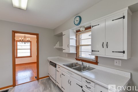 A kitchen with white cabinets and a clock on the wall.