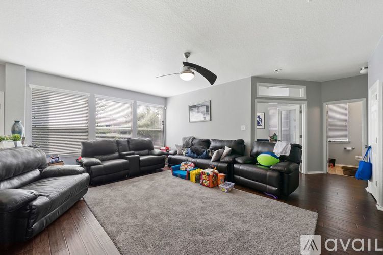 A living room with a grey rug and two black leather sofas.