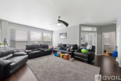 A living room with a grey rug and two black leather sofas.