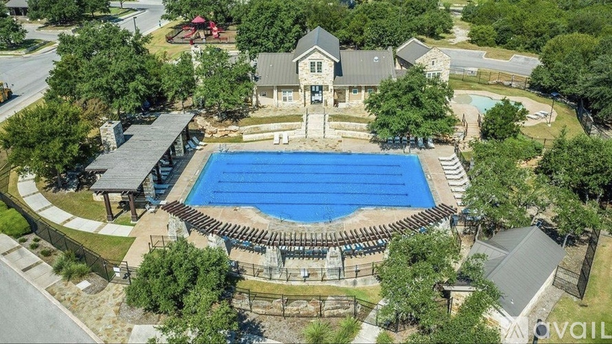 A large swimming pool surrounded by a fence and trees.