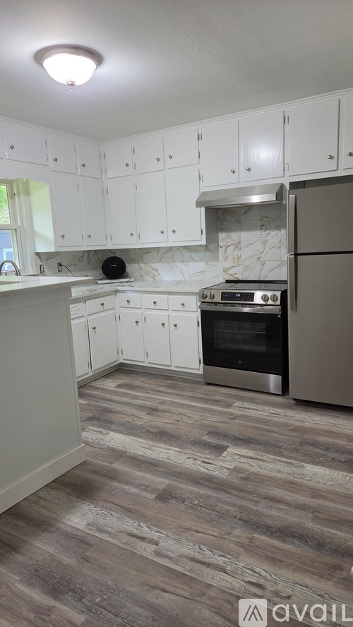 A kitchen with white cabinets and a stainless steel refrigerator.