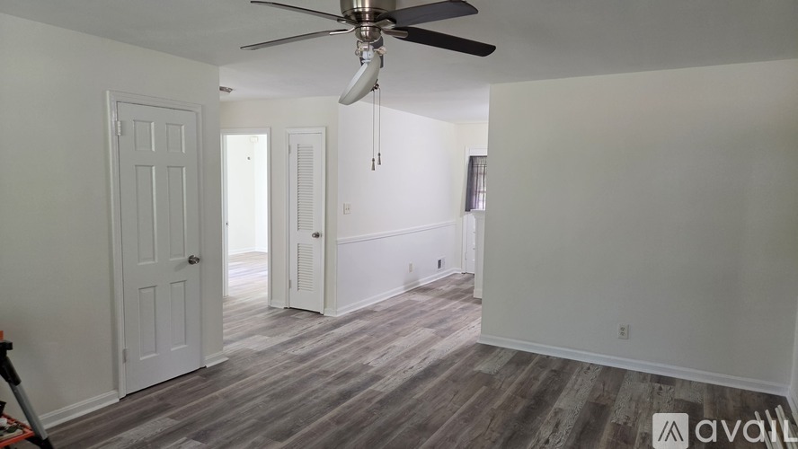 A room with a ceiling fan and wooden flooring.