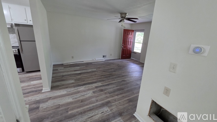 A room with a ceiling fan and a red door.