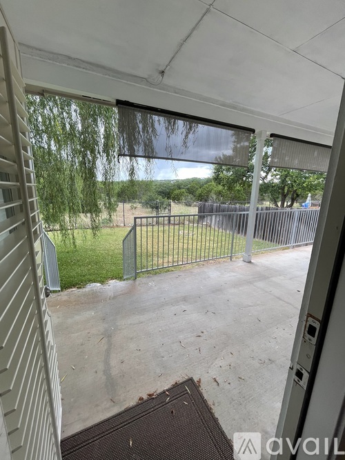 A patio with a metal gate and a view of a fence and trees.