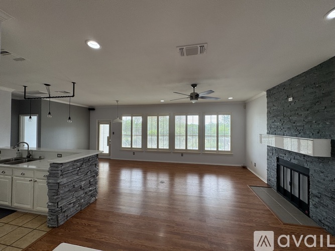 A spacious living room with a stone fireplace and hardwood floors.