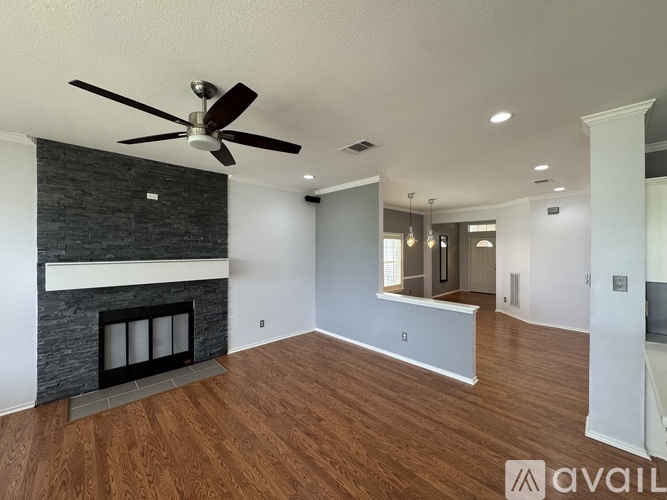 A spacious room with a fireplace and a ceiling fan.
