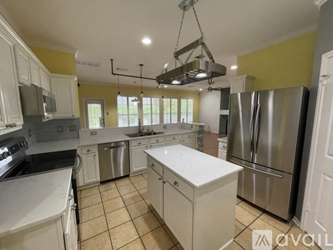 A kitchen with white cabinets and a stainless steel refrigerator.