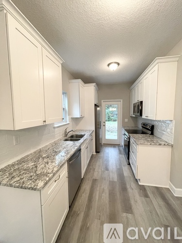 A kitchen with white cabinets and a granite countertop.