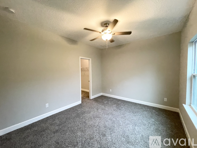 A room with a ceiling fan and carpeted floor.