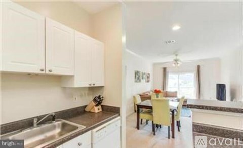 A kitchen with white cabinets and a dining area with yellow chairs.