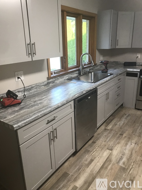 A kitchen with white cabinets and a marble countertop.