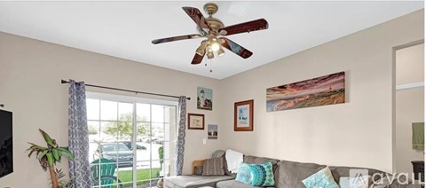 A living room with a grey couch and a ceiling fan.