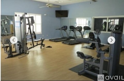 A gym with a variety of equipment including treadmills, weights, and a television.