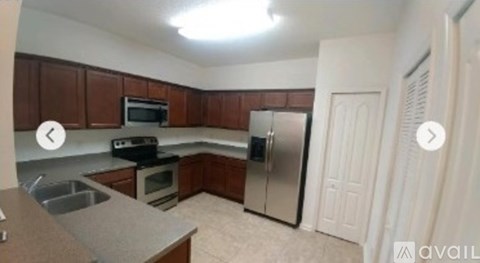 A kitchen with brown cabinets and a stainless steel refrigerator.