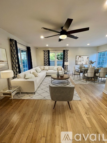 A living room with a white sofa, a grey armchair, and a wooden floor.