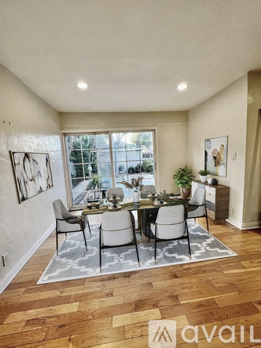 A dining room with a table set for six and a view of a backyard.