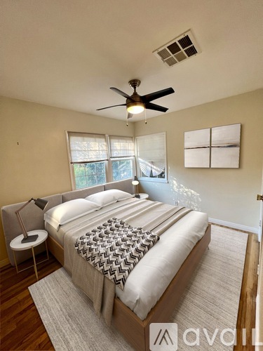A bedroom with a large bed and a ceiling fan.