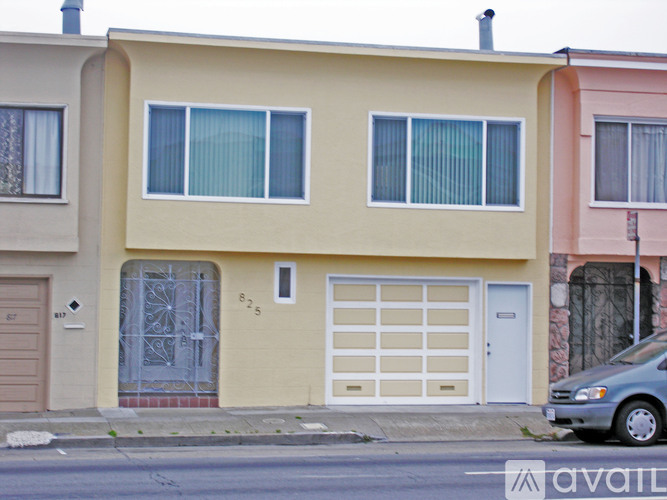 A yellow house with a garage door and a car parked in front.