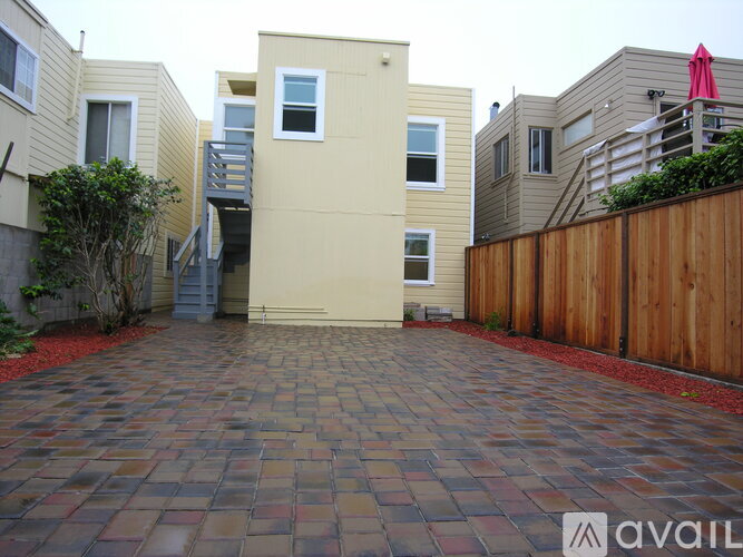 A brick driveway leads to a house with a wooden fence on the right.