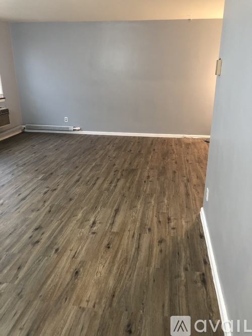 A room with wooden flooring and white walls.