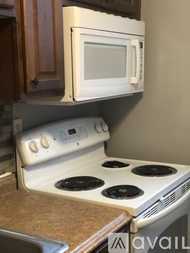A white microwave oven is mounted above a white gas stove in a kitchen.