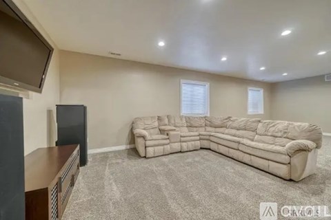 A living room with a large sectional sofa and a flat screen TV.