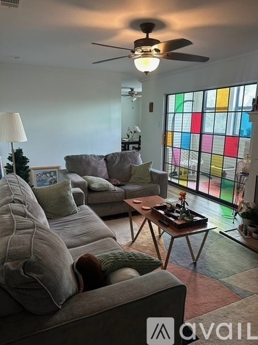 A living room with a grey couch and a coffee table in front of a stained glass window.