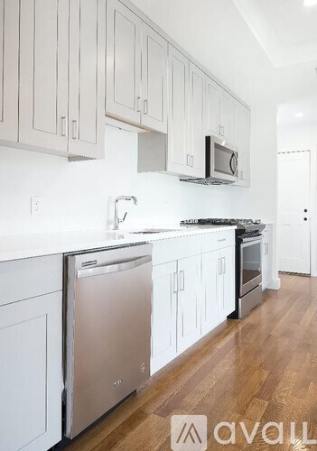 A kitchen with white cabinets and a wooden floor.