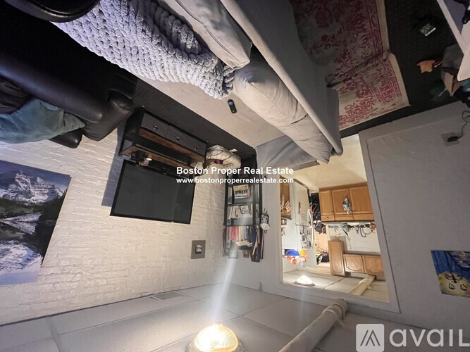 A room with a bed and a window, with a sign that says "Boston Proper Real Estate".