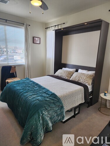 A bedroom with a large bed and a window with blinds.