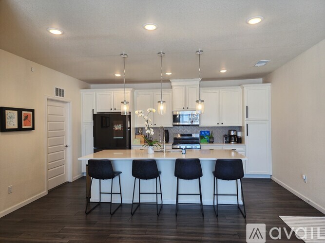 A kitchen with a black refrigerator and white cabinets.