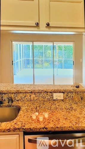A kitchen with a granite counter top and a window.