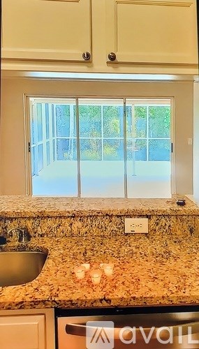 A kitchen with a granite counter top and a window.