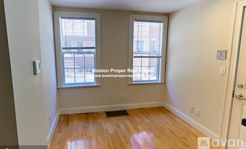 A room with wooden floors and two windows, one of which is open.