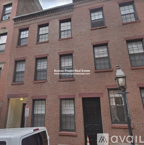 A red brick building with a white van parked in front.