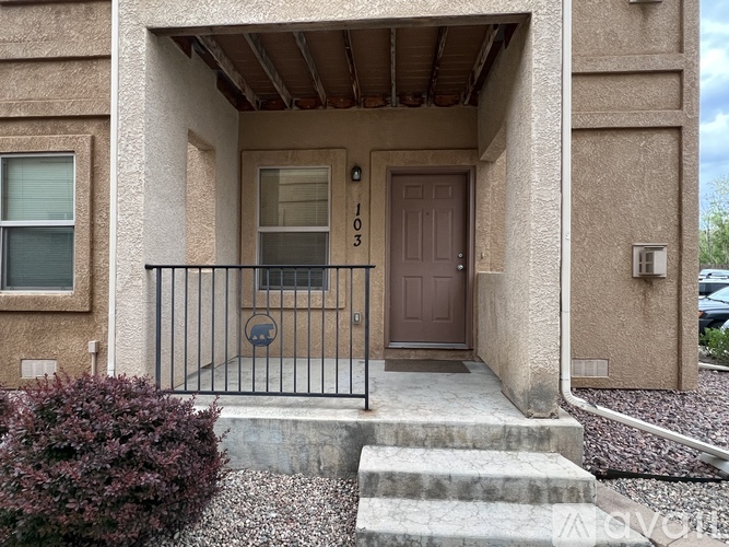 A brown door with a black railing is on the front of a house.