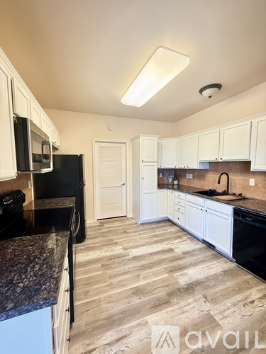 A kitchen with black appliances and white cabinets.