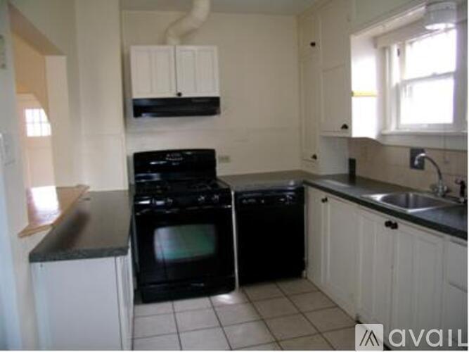 A kitchen with black appliances and white cabinets.