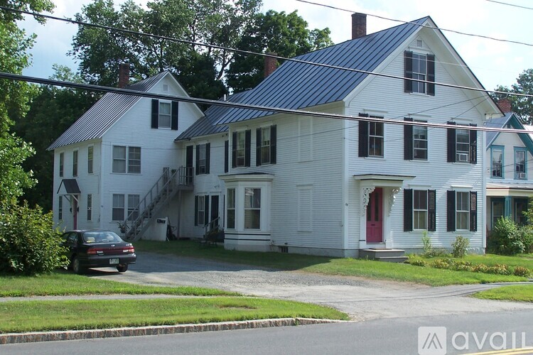 A white house with a red door and a car parked in front.