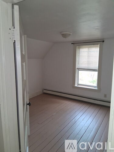 A room with a window and wooden flooring.