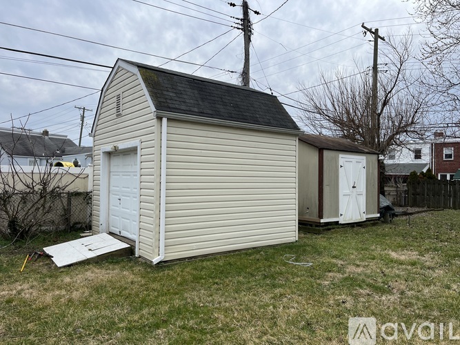 A shed with a white door is in a grassy area.