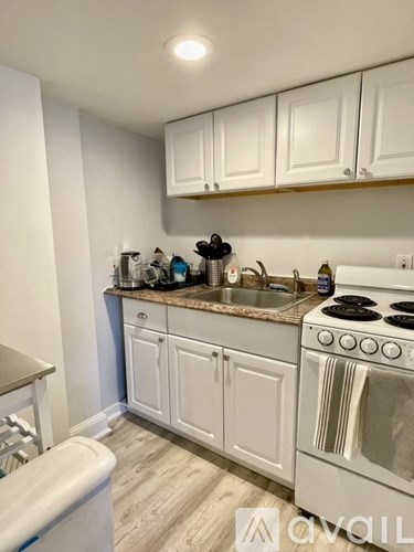 A kitchen with white cabinets and a white stove top oven.