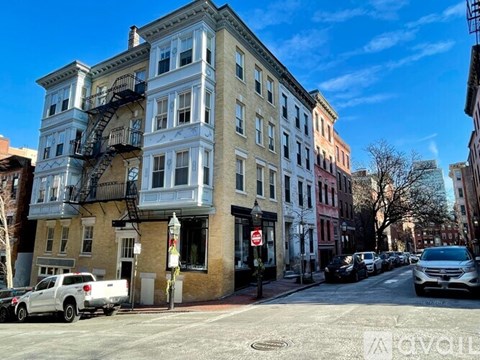 A street view of a row of buildings with cars parked on the side of the road.