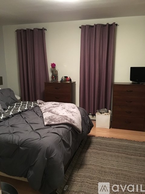 A bedroom with a bed, nightstand, and a dresser with a TV on it.