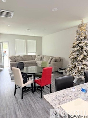 A living room with a Christmas tree and a glass table with chairs.