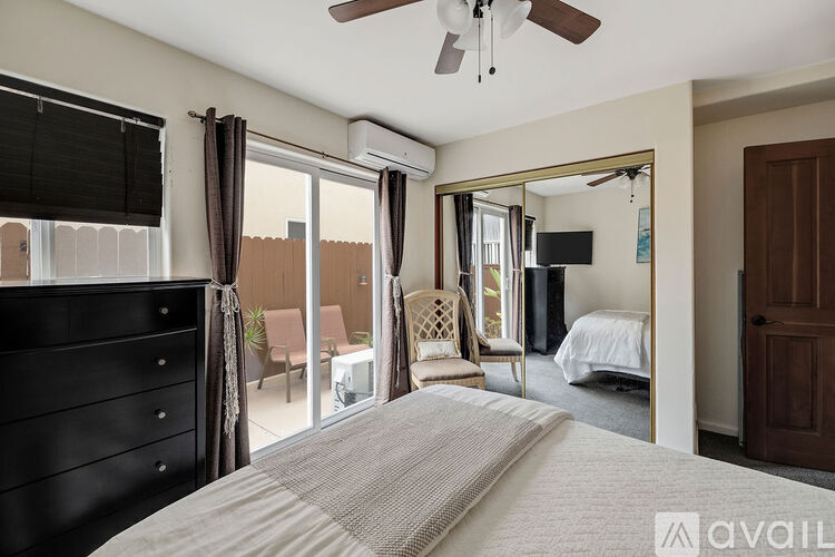 A bedroom with a large bed and a sliding glass door leading to a balcony.