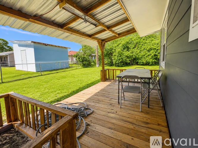 A wooden deck with a table and chairs is covered by a roof.