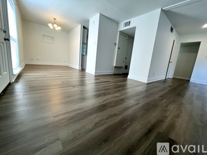 A spacious room with wooden flooring and white walls.