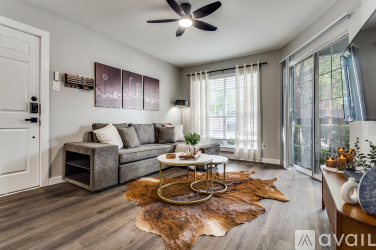 A living room with a grey couch, a brown cowhide rug, and a ceiling fan.