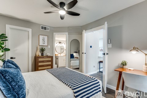 A bedroom with a bed, desk, and mirror.